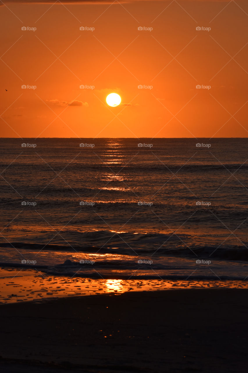 sunrise at dawn near ocean sea shore yellow sun orange sky and blue waves in morning