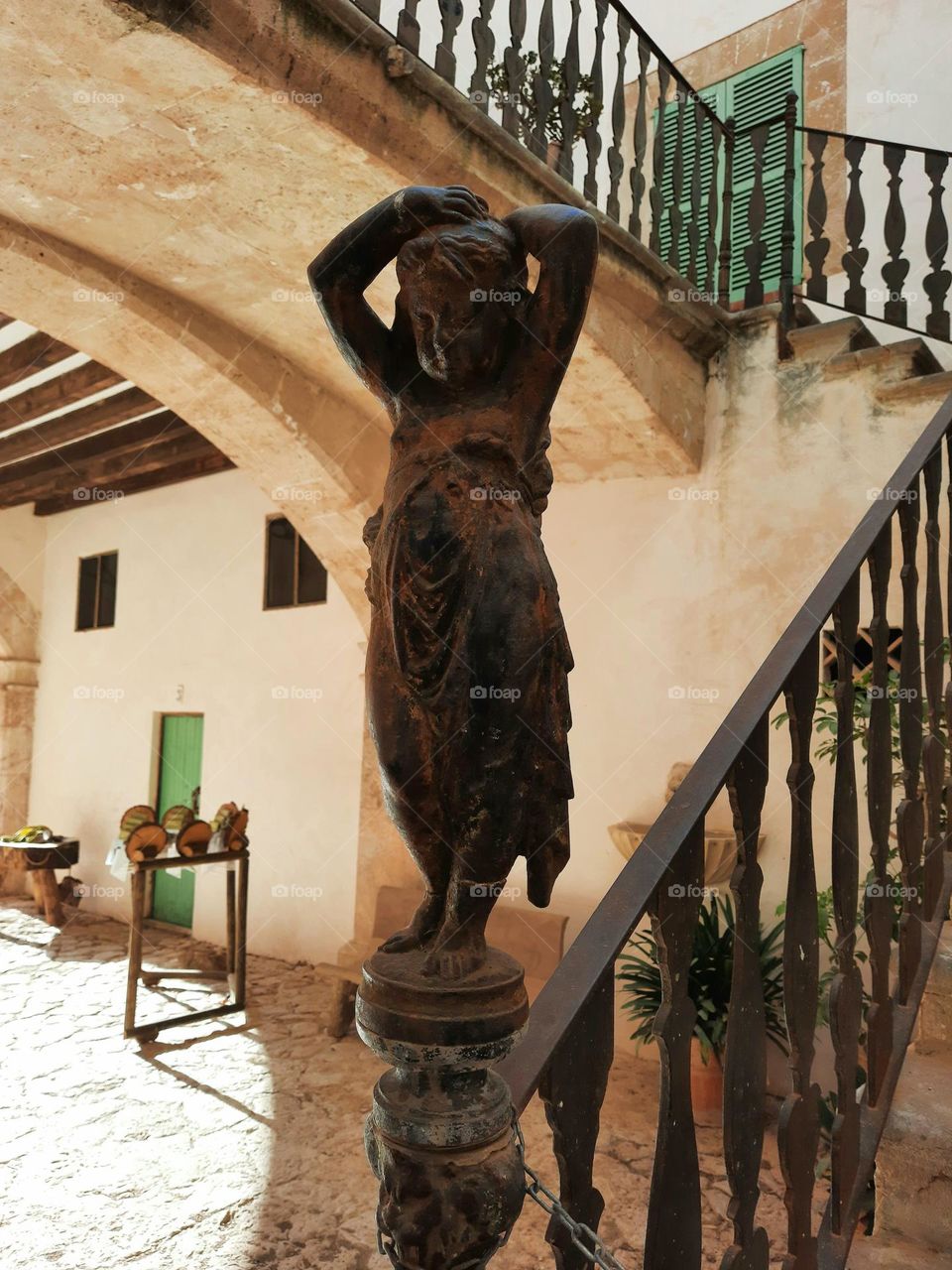 Cast iron figure of a young girl at an ancient staircase. Situated at a courtyard of a Mediterranean traditional manor. Calvia, Majorca, Spain.
