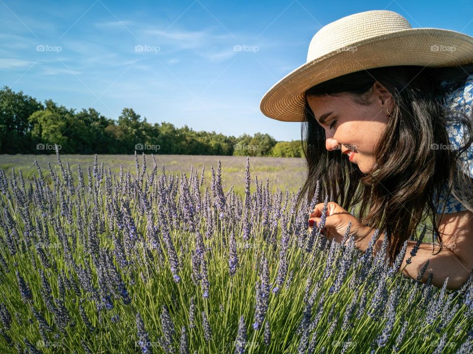 Portrait of happy young woman smelling lavender flowers in a filed outdoor