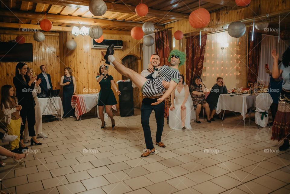 funny moment during a wedding when the groom holds his disguised friend in his arms