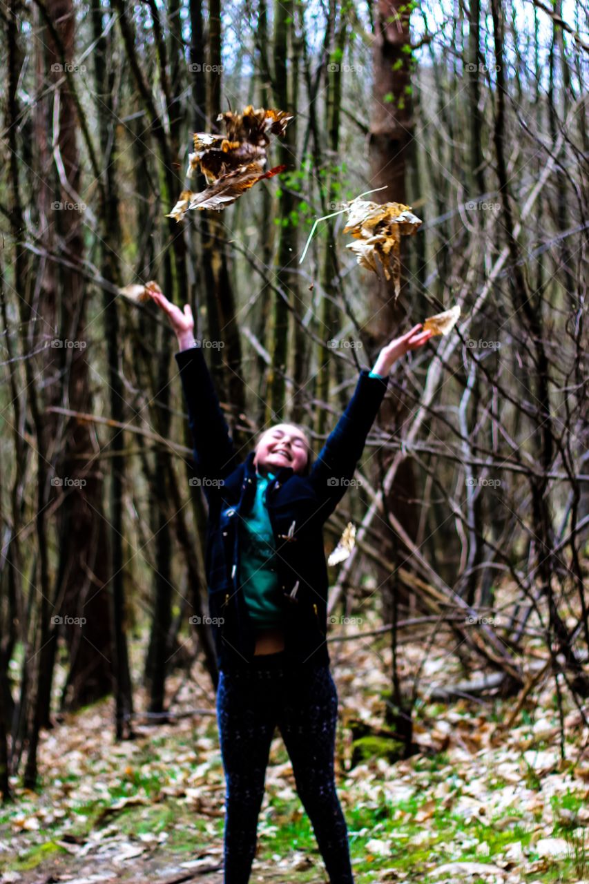 Smiling girl throwing the dry autumn leaves