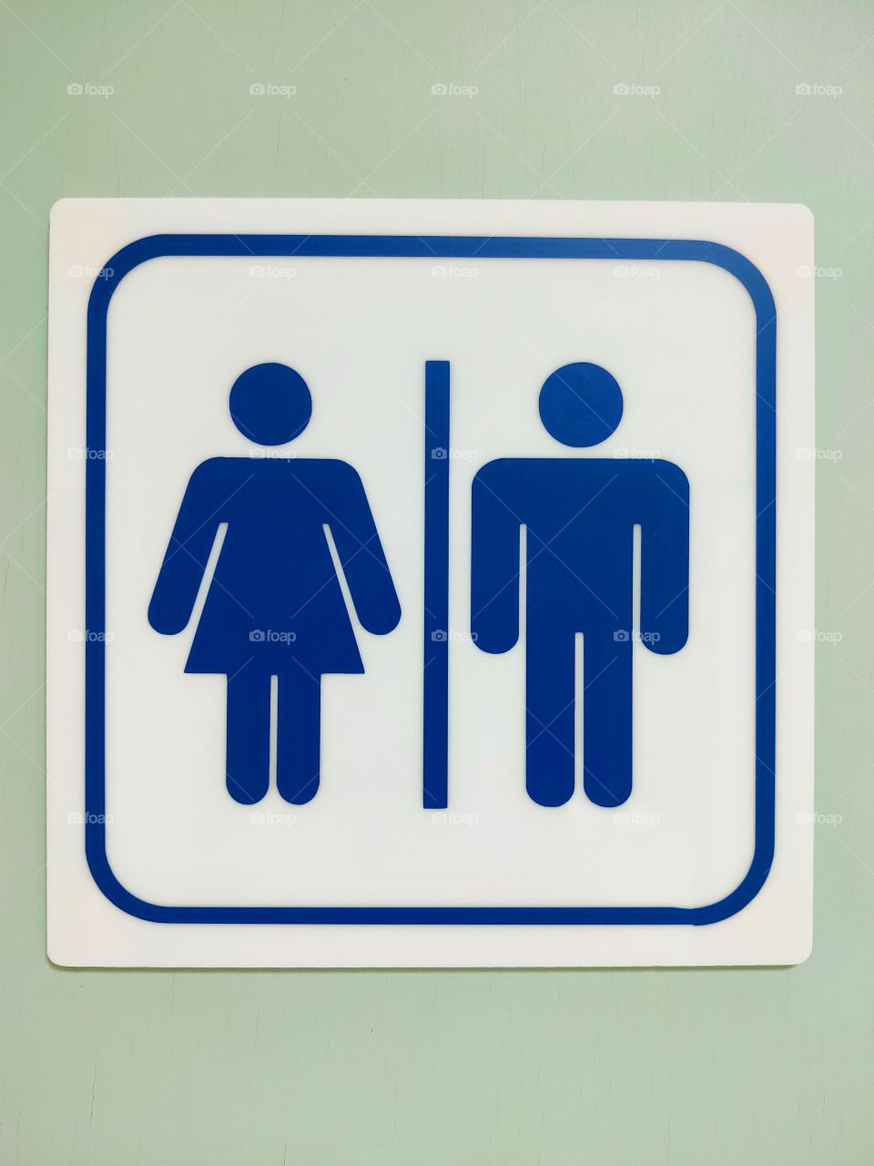 Blue male and female stickers on a white background, placed in front of a public bathroom.