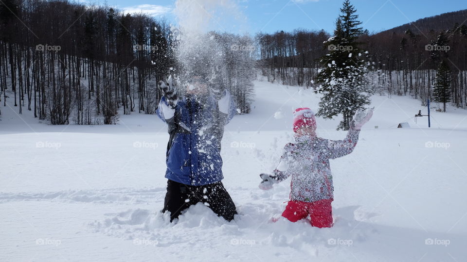 Dad and daughter have playing with the snow in a snowy day at the mountains 