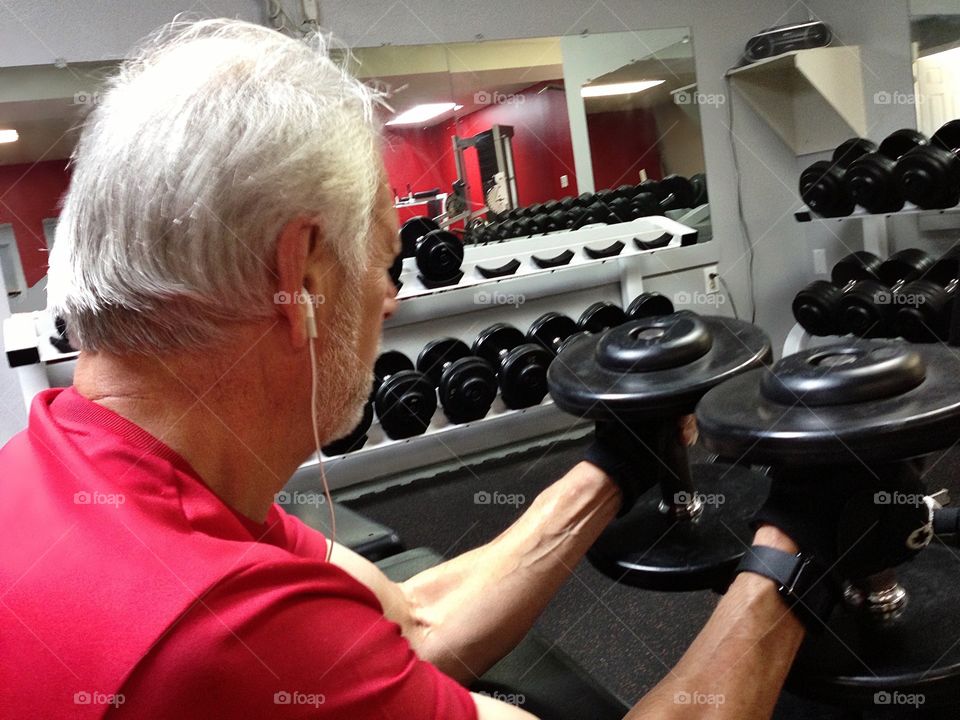 Man pumping iron with black barbells.