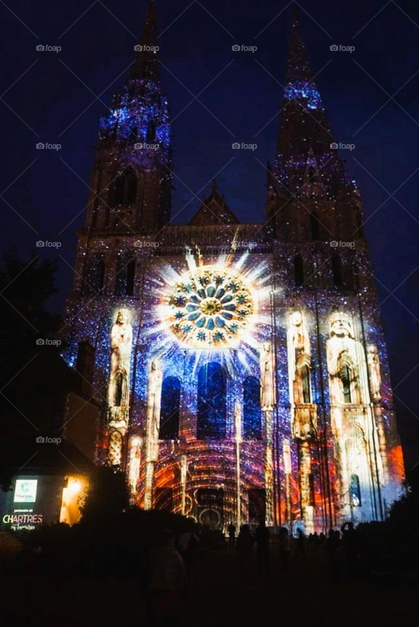 Colourful illuminations on the facade of Notre-Dame de Chartres' cathedral in Chartres under a navy blue sky