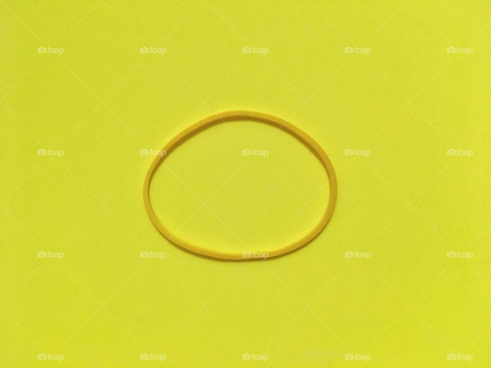 Minimalism; Yellow rubber band on a plain yellow background 