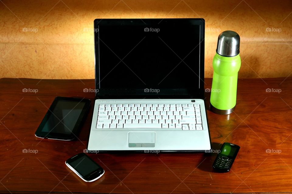 laptop computer, tablet, cellphone, smartphone and a flask on a living room table