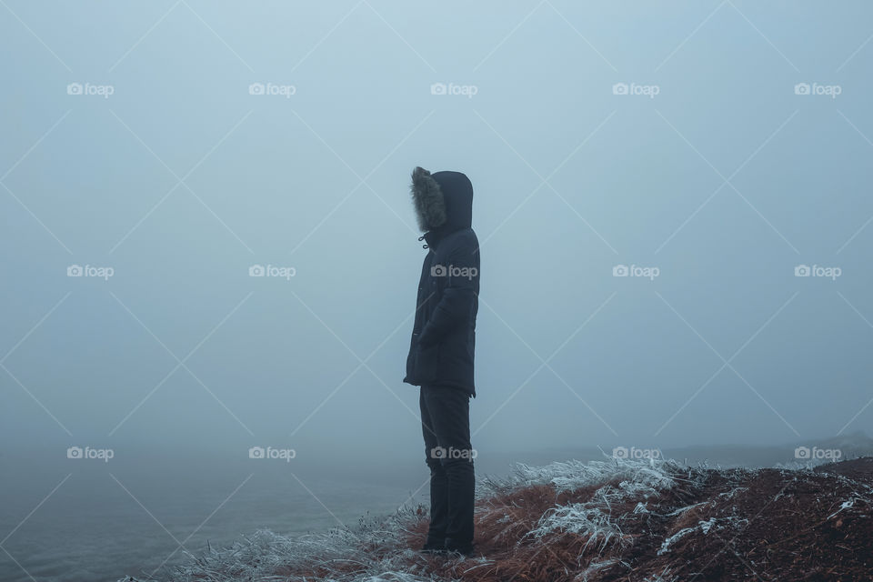 Man standing on field during foggy weather.
