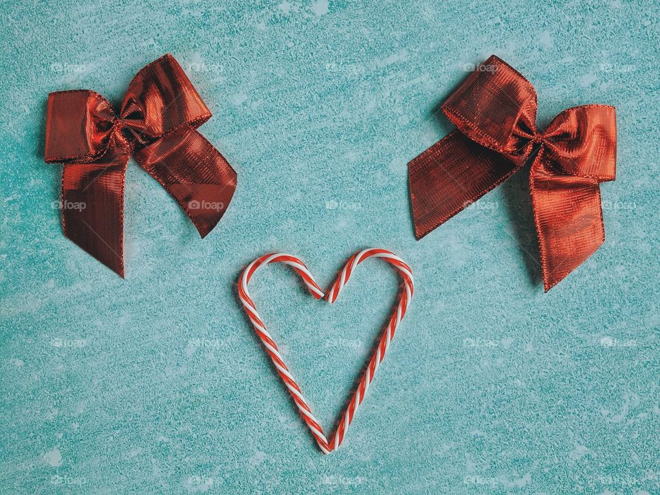 Festive blue background. Heart of sweet candies. Red bow. Winter postcard. Christmas card. Valentine day. 14 of February. Top view.