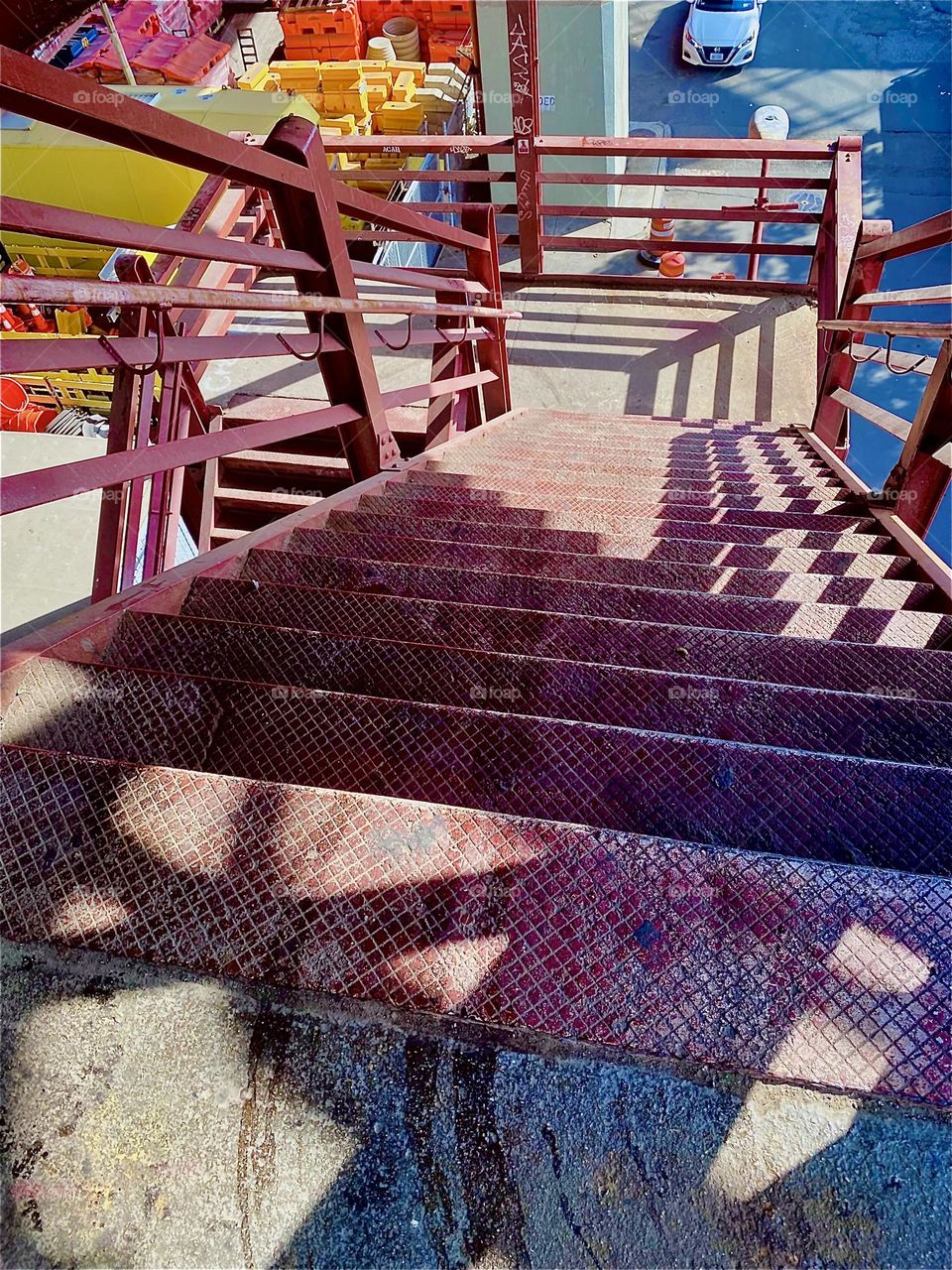 This expressionistic cubist inspired photograph is a view of the metal staircase leading down onto the parking lot beneath the „Pulaski Bridge“ at „Newtown Creek“ in LIC, Queens. Shapes and shadows combine beautifully here. 2023. Hypnotic Productions