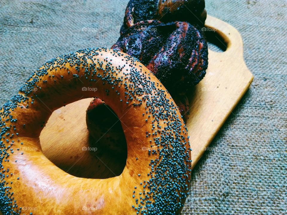 A bagel with poppy seeds and a basket with poppy seeds lie on the table