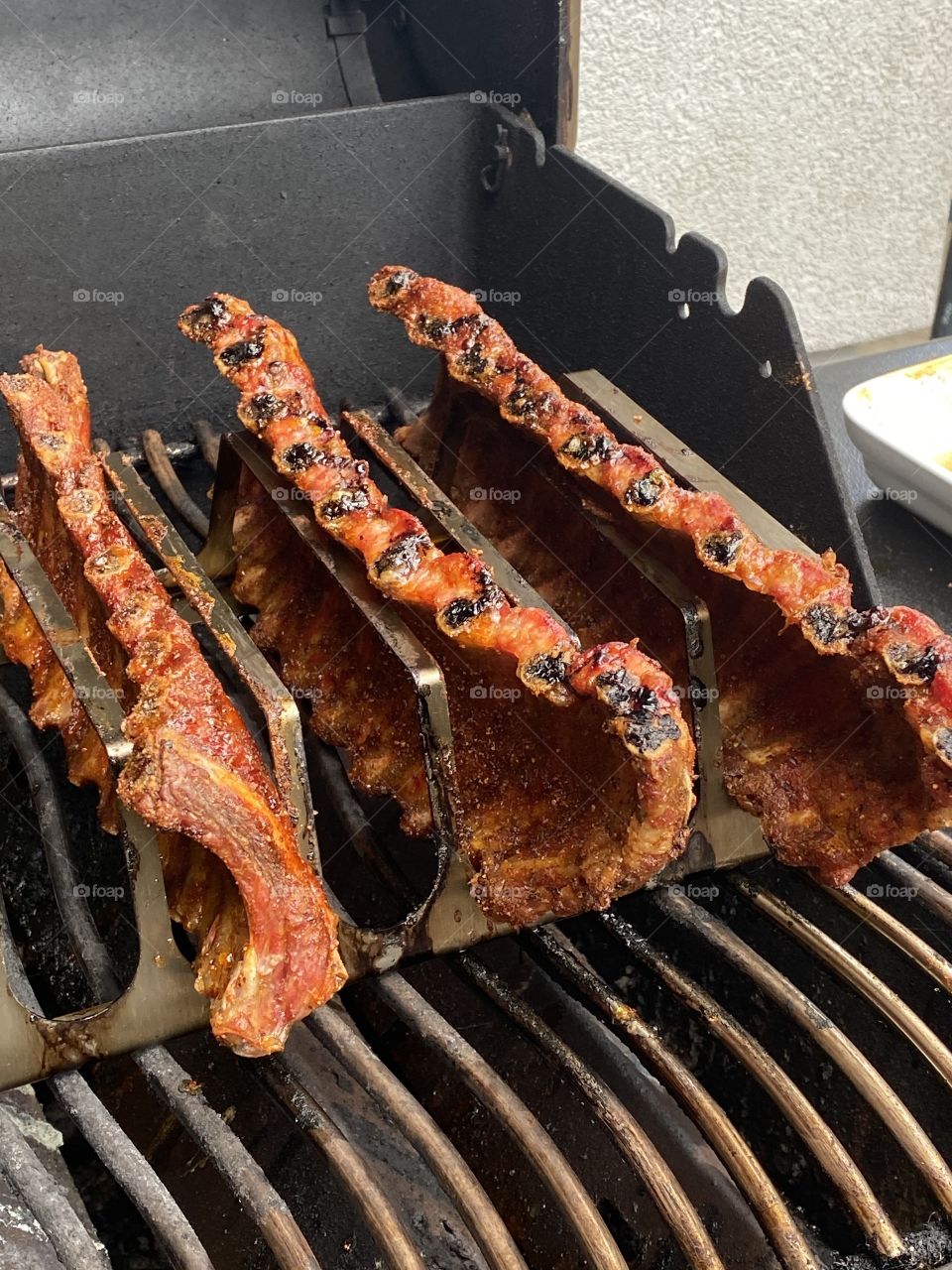 Grilled spareribs standing in a rack on a barbecue with homemade rub 