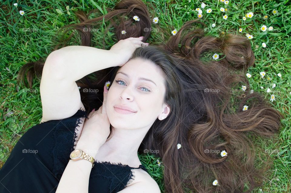 Portrait of Beautiful Young Girl on Background of Daisies