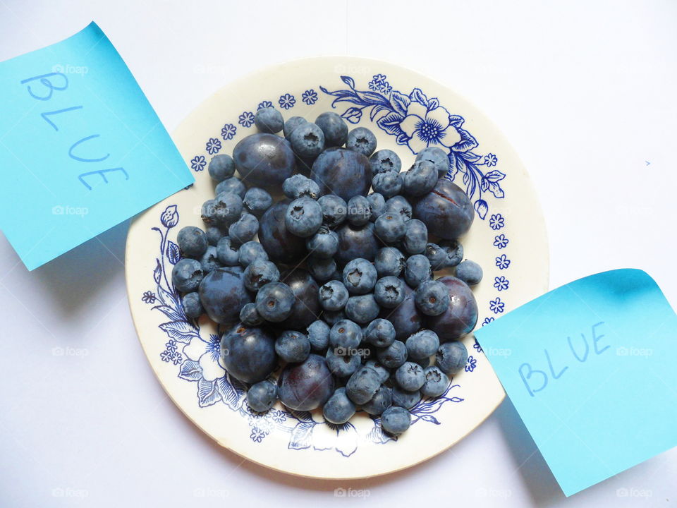 Berries of blueberries and plums on a white plate