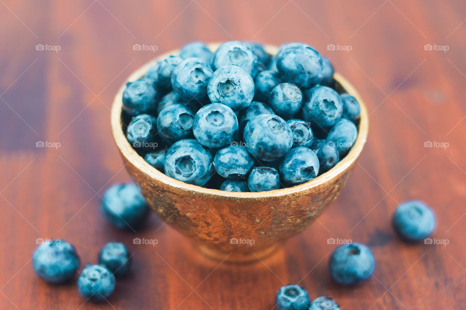 Fresh Blueberries in a Gold Bowl on a Wood Table