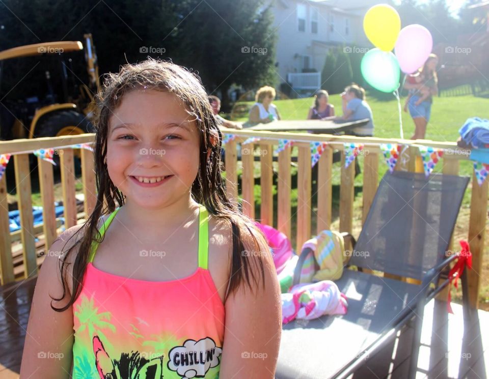 Birthday Girl. Young lady smiling for the camera at her birthday pool party. 