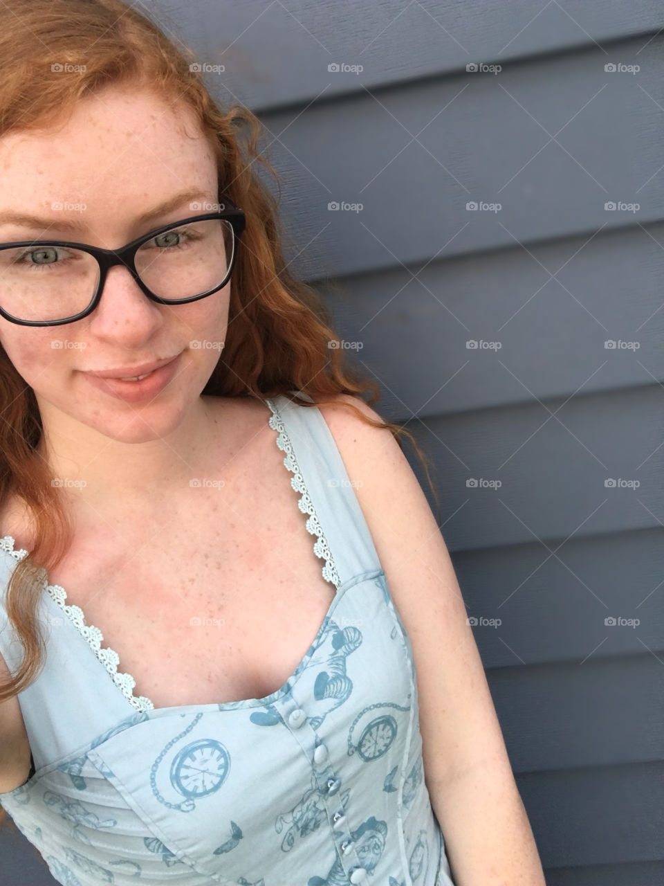 Picture of me: red head, blue eyes, freckles, and glasses wearing blue dress with dark blue background