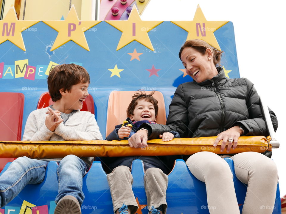 Mother with her sons enjoying ride in amusement park