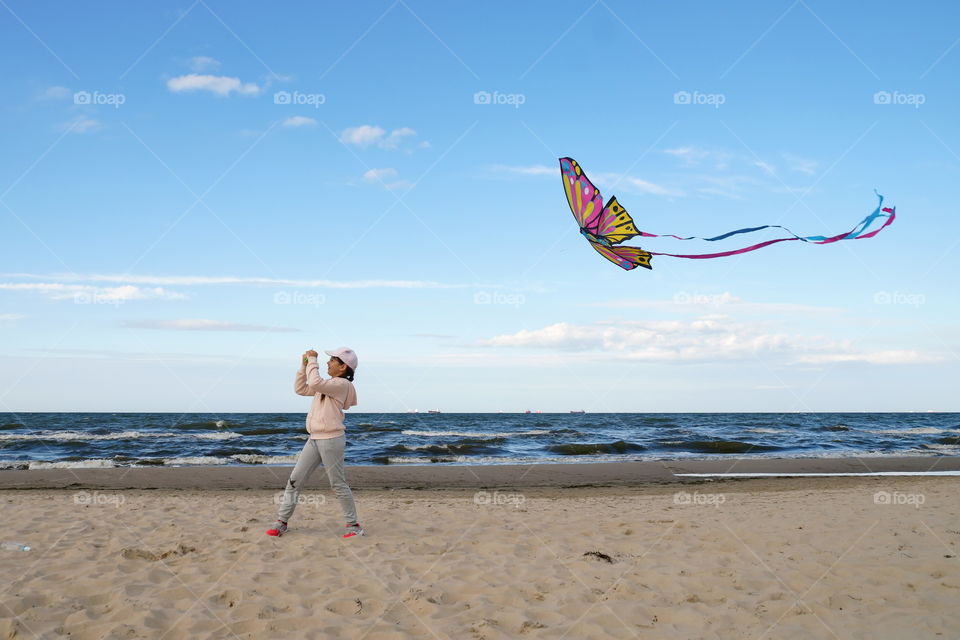 Girl on the seashore launches a kite