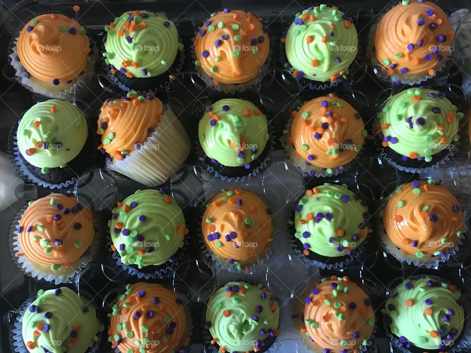 Celebrating with Cupcakes, birthdays and holidays. Cupcakes with orange and green frosting with sprinkles. 