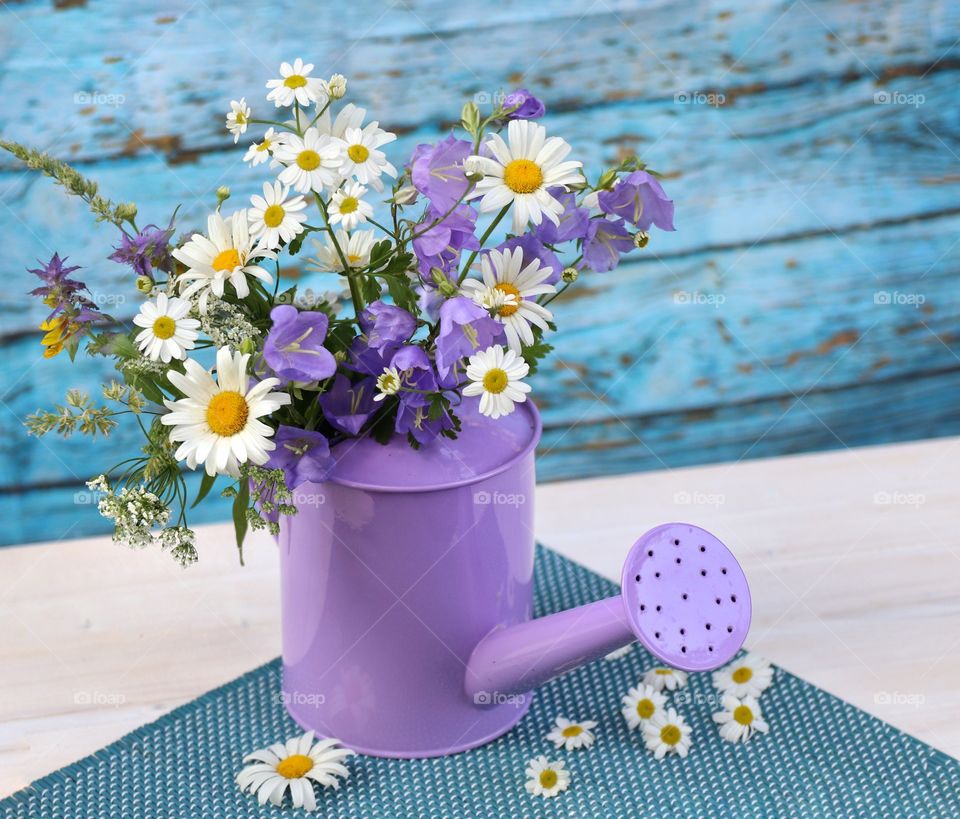 Bouquet of wild flowers in a lilac watering can