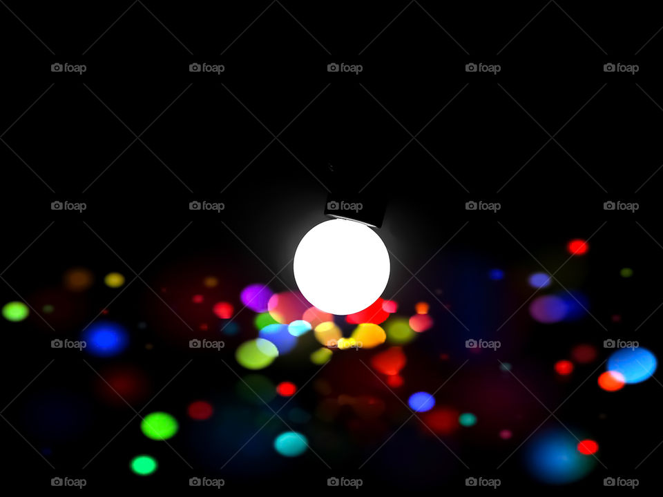 Light up the colors!  Concept photo:  A round light bulb uncovering colorful lights in a dark room.