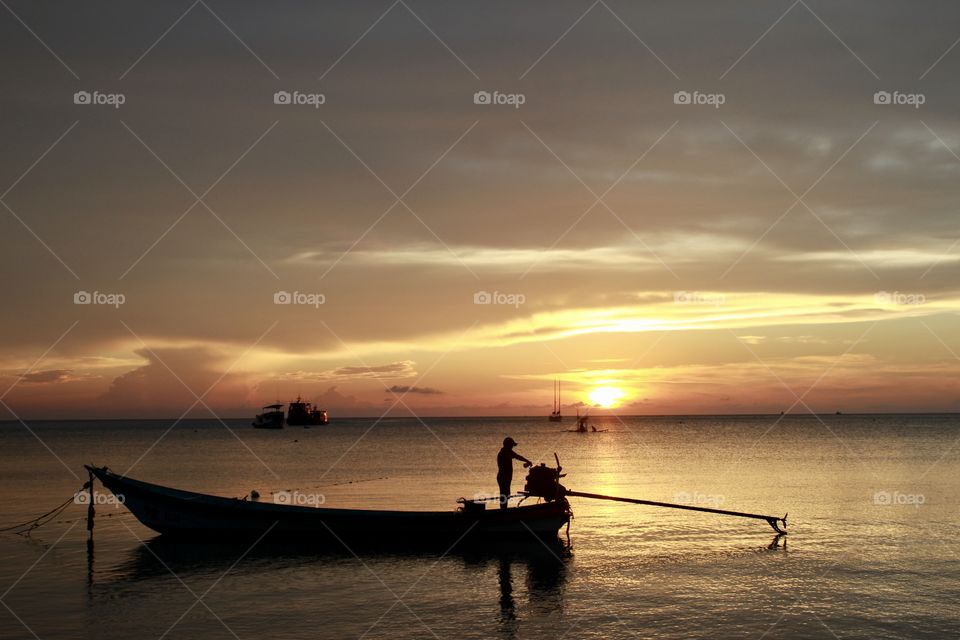 Golden hour in Koh Tao, Thailand. A beautiful colourful sunset, you can feel the peace and the local customs. Small boats.