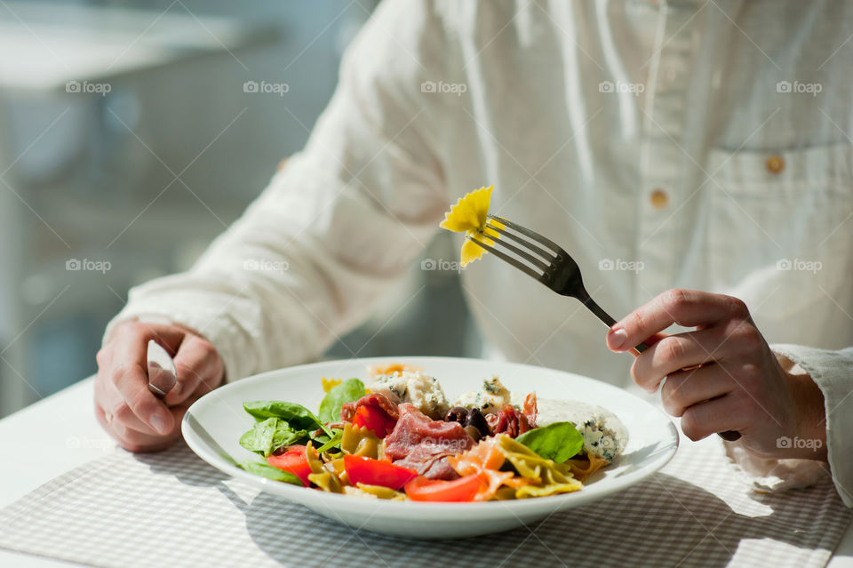 close-up of a young man eating a salad in a light kitchen