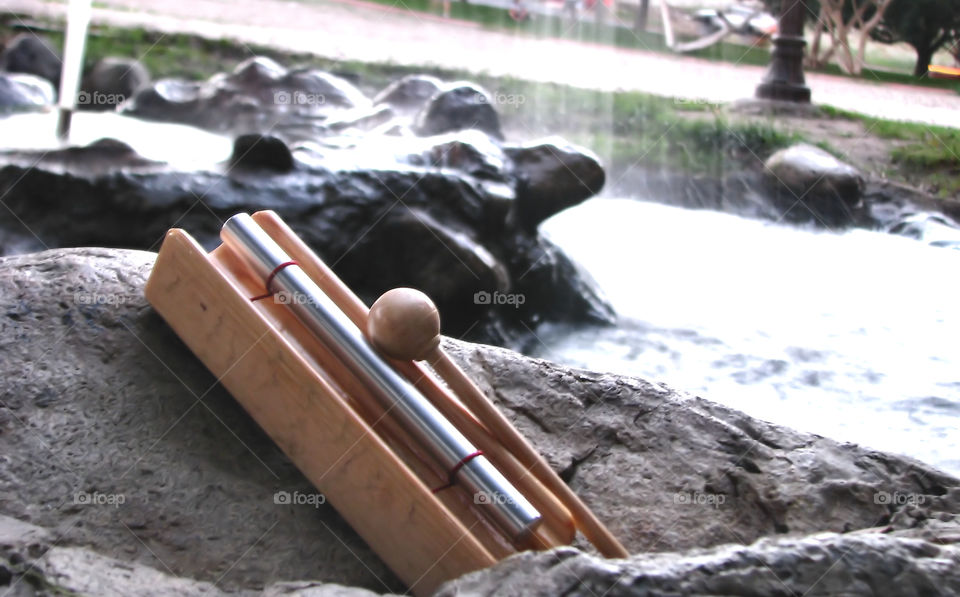 Musical instrument with stick on rock near water fountain