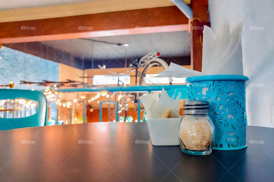 A nice table with sugar and napkins, with a beautiful view of the coffee shop in the morning