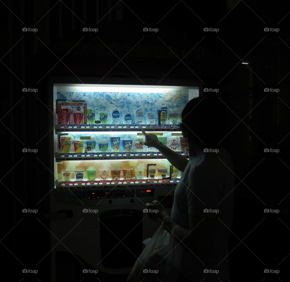 Harajuku, Tokyo, Japan.  Late night vending machine, young man pointing at choices