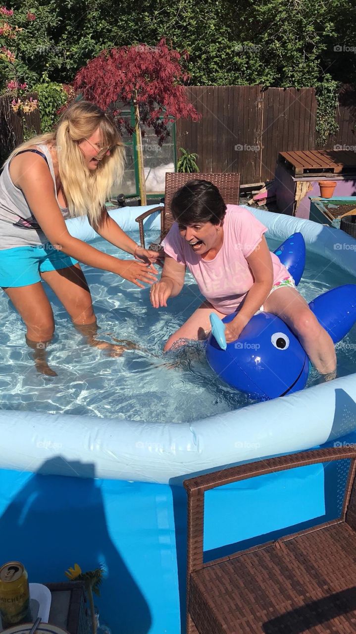 Mum and daughter in a fit of giggles ‘ as mum can’t balance on the pool toy 