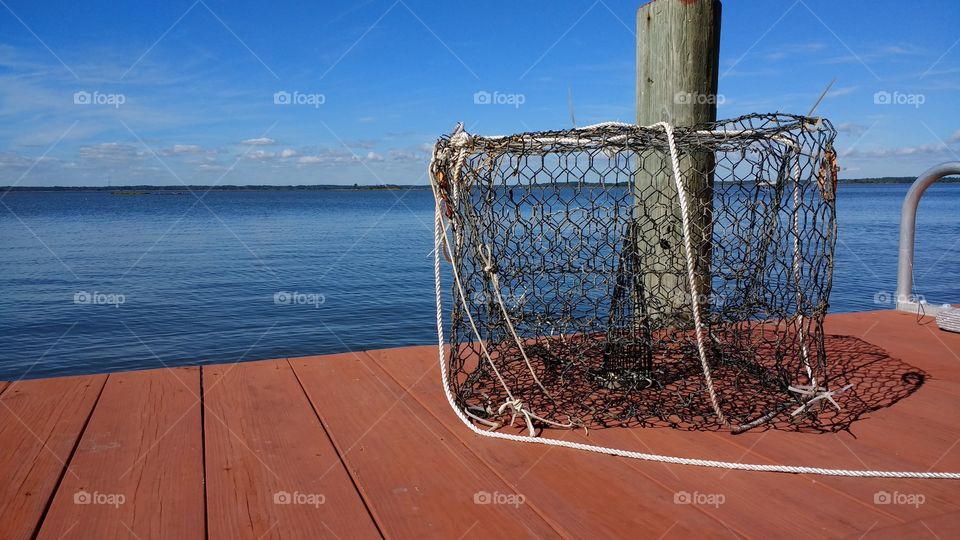 Empty crab pot on wooden dock overlooking Assawoman Bay in Ocean City, MD