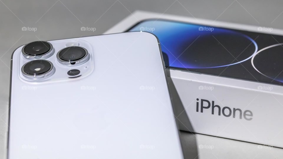 The all new iPhone 14 Pro Max in silver. Placed on the original packaging box. Large triple lens cameras. Isolated on plain white background. Released by Apple in September 2022.