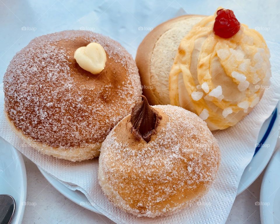 Yummy and delicious krapfen donuts filled with creams and chocolate, covered with sugar grains 