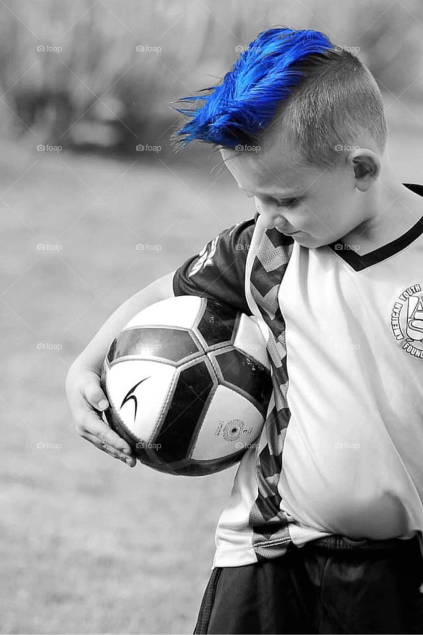 Blue is not just a color, it’s an attitude! Tough little soccer player looking down at his ball. 