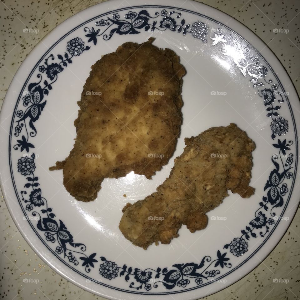 Two boneless pieces of fried chicken on a plate. Definitely they appear good to eat.