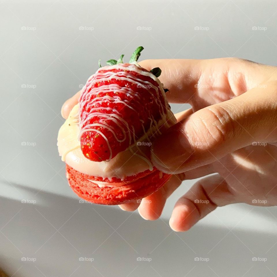 Holding on to a strawberry cheesecake fat macaron under the sunlight 