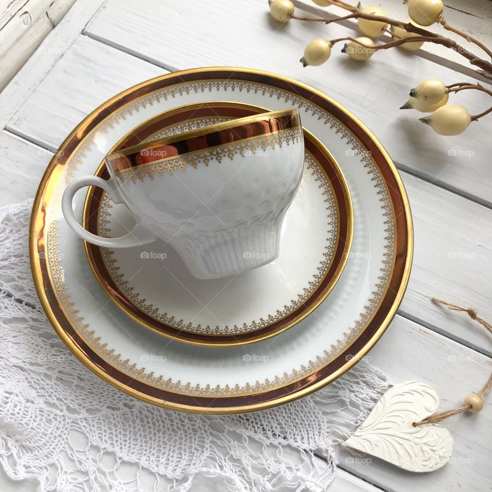 Antique porcelain set - cup, saucer and plate with golding, ornament and reliefs.