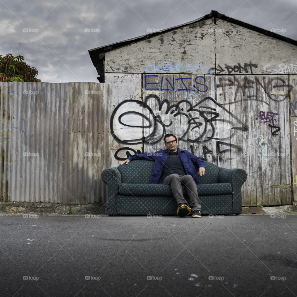 Close-up of man sitting on sofa against corrugated wall