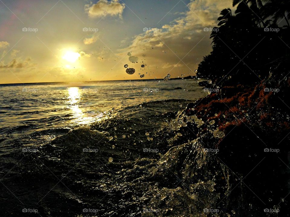 Waves splashing against rocks at sunset