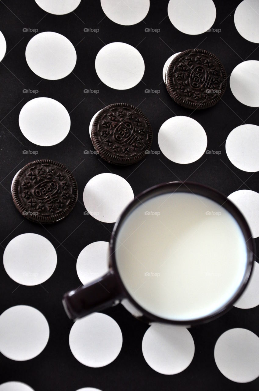 oreo cookies with milk flat layout on black surface with white dots