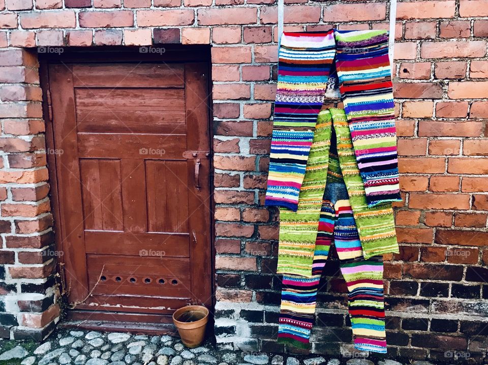 Stripy woolen pants hanging on a brick wall next to a door