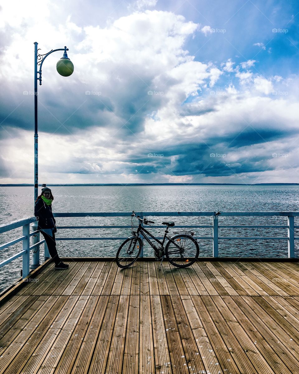 Woman in warm clothing on wooden pier with bicycle