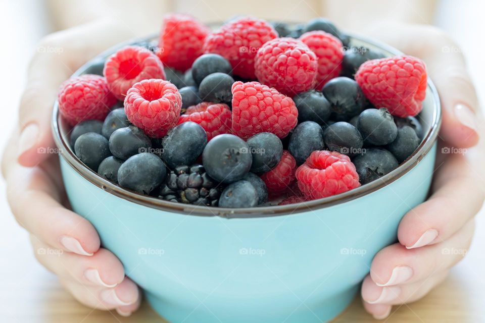 Bowl of fresh berries in female hands