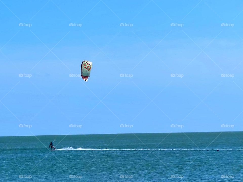 Summer.  Sea.  Kitesurfing.  In the sea, on the waves, a man moves, who controls a kite