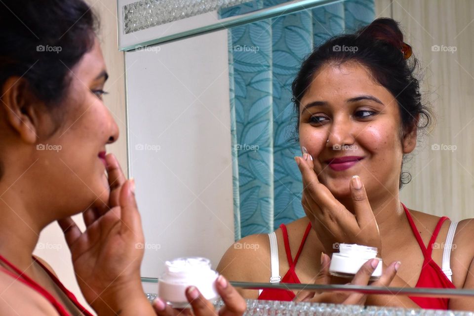 Indian woman applying face cream in her face