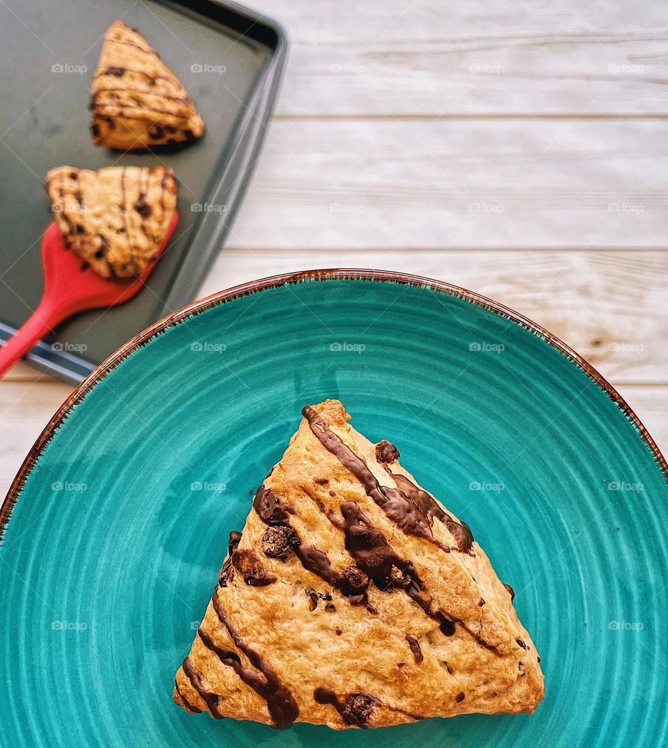 Scone on a plate, freshly baked chocolate chip scones, holding a plate with a scone on it, smartphone food photography, chocolate chip scones, baking at home, making homemade scones, baking in the kitchen, delicious chocolate chip scones