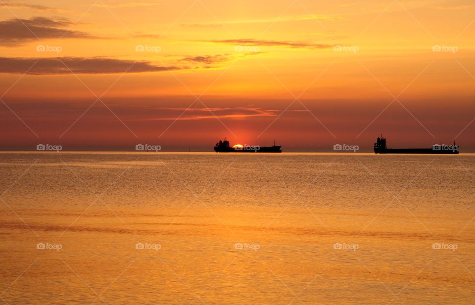 Beautiful bright sunrise over the Baltic in Gdynia, Poland - shops on horizon, silhouettes and calmness 