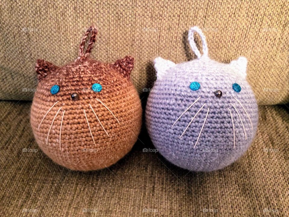 Close up macro of two handmade crocheted sphere toy persian cats with blue eyes and whiskers